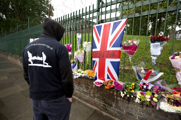 TRIBUTE. A man wearing Help the Heroes shirt looks at floral tributes left at the scene where Drummer Lee Rigby of the 2nd Battalion was killed outside Woolwich Barracks in London on May 24, 2013. Photo by Justin Tallis/AFP