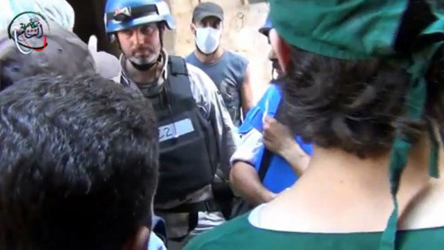 An image grab taken from a video uploaded on YouTube on August 26, 2013 allegedly shows a UN inspector (C) listening to the testimony of a man in the Damascus subburb of Moadamiyet al-Sham. AFP PHOTO / YOUTUBE 