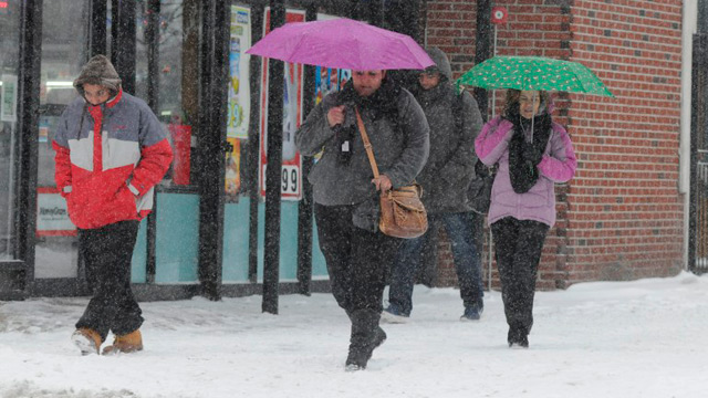 People walk in Maverick Square as a snowstorm begins January 2, 2014 in East Boston, Massachusetts. Darren McCollester/Getty Images/Agence France-Presse