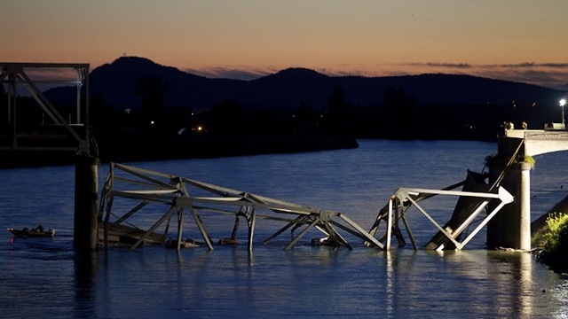 PLUNGING STRUCTURE. A boat cruises past the scene of a bridge collapse on Interstate 5 on May 23, 2013 near Mt. Vernon, Washington. 1-5 connects Seattle, Washington to Vancouver, B.C., Canada. Stephen Brashear/Getty Images/AFP