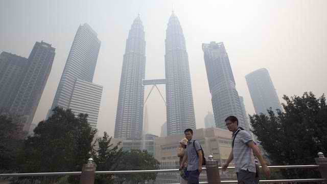 HAZY SKYLINE. Visitors walk through a park near Petronas Towers which is just visible through the haze in Kuala Lumpur, Malaysia 23 June 2013. Photo by EPA/Ahmad Yusni