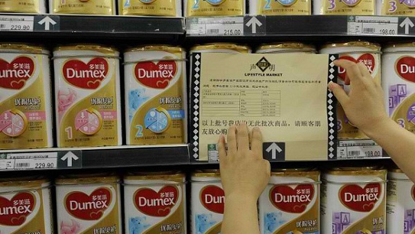 DOUBLE CHECK. A woman checks a guarantee announcement on a shelf of Dumex baby formula, which uses the New Zealand dairy Fonterra as its raw material supplier, at a supermarket in Hefei, north China's Anhui province, on August 5, 2013. Photo by AFP