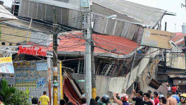 COLLAPSED. People gather on the street next to damaged buildings in Cebu City, Philippines after a major 7.1 magnitude earthquake struck the region on October 15, 2013. AFP