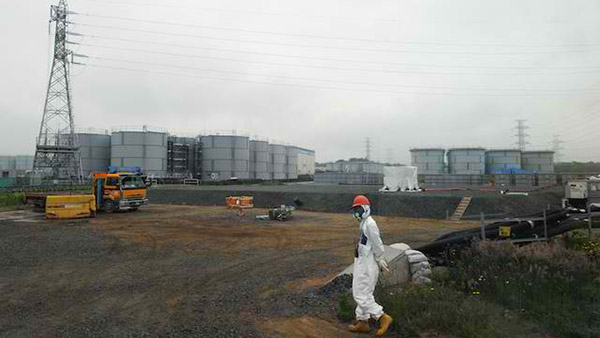 A construction worker walks beside the underground water tank and water tanks at the Fukushima Dai-ichi nuclear plant at Okuma town in Fukushima prefecture on June 12, 2013. EPA/Toshifumi Kitamura