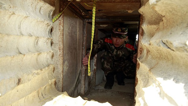 CHINA, Shenzhen : This picture taken on December 24, 2013 shows a soldier checking an underground tunnel leading to Hong Kong from Shenzhen, south China's Guangdong province. Chinese smugglers dug a 