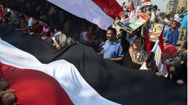 NEW EGYPT PROTESTS. Egyptians wave a giant national flag on Tahrir Square as they mark the 40th anniversary of the 1973 Arab-Israeli war on October 6, 2013 in the Egyptian capital Cairo. AFP / Khaled Desouki