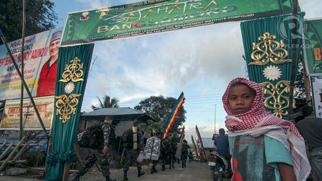 WAITING FOR PNOY. A young Moro stands at the entrance of the venue of Sahajatra Bangsamoro in Sultan Kudarat town in Maguindanao as members of the PSG march to secure the area. Photo by Karlos Manlupig.