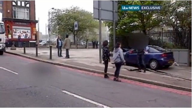 BRAVE. Bystanders talk to one of the the alleged suspects (blurred person, right) in the death of a British soldier (blurred person, left) in London, May 22, 2013. Frame grab from ITV News video