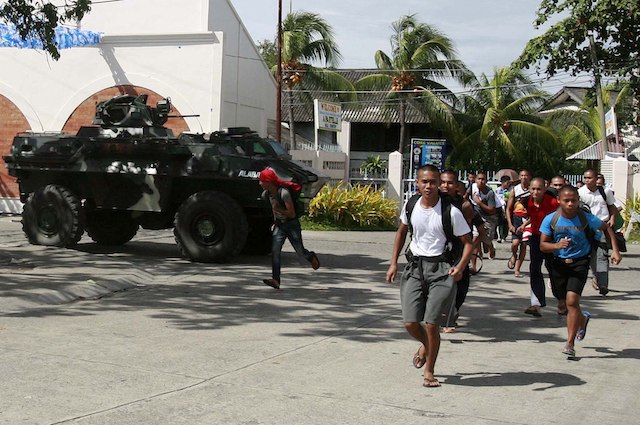 RUSHING TO SAFETY. Students run pass an armored military vehicle as they evacuate from a compound near an area where members of the Moro National Liberation Front (MNLF) occupied villages in Zamboanga City, southern Philippines, 09 September 2013. EPA/Laurenz Castillo