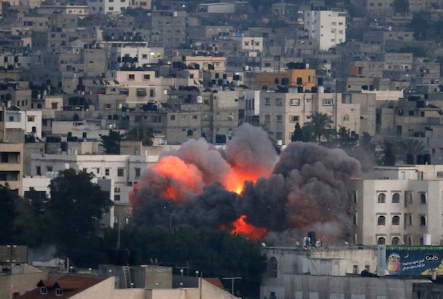 WAR. Flames erupt from a building hit by an Israeli air strike on July 9, 2014 in Gaza City. Thomas Coex/AFP