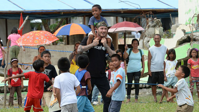BECKHAM IN LEYTE. English football superstar David Beckham (L) chases a boy during a football game with children-survivors of super Typhoon Yolanda at a school ground in Tanauan town, Leyte province, central Philippines on February 14, 2014, on the second day of his visit to the super typhoon stricken province. Beckham who flew to the Philippines on February 13 to give comfort to survivors of the Asian country's deadliest ever typhoon, gamely played with a dozen children-survivors. Photo by Ted Aljibe/AFP