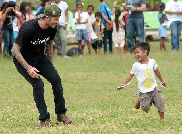 English football superstar David Beckham (C) carries a boy on his shoulders during a football game with children-survivors of super Typhoon-Haiyan at a school ground in Tanauan town, Leyte, central Philippines on February 14, 2014, on the second day of his visit to the syper typhoon stricken province. Beckham who flew to the Philippines on February 13 to give comfort to survivors of the Asian country's deadliest ever typhoon, gamely played with a dozen children-survivors. Photo by Ted Aljibe/AFP