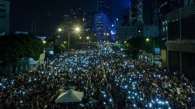 DEFYING RAIN. Pro-democracy protestors hold up their mobile phones after heavy rain in Hong Kong on September 30, 2014. Photo by Anthony Wallace/AFP 