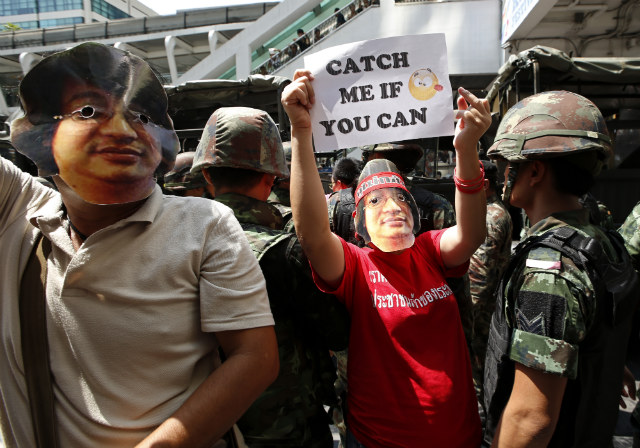 'CATCH ME IF YOU CAN.' Thai demonstrators wear masks of a military wanted list activist, Sombat Boonngamanong, as they hold placards next to soldiers during a demonstration against the coup at a shopping district in Bangkok, Thailand, May 25, 2014. File photo by Rungroj Yongrit/EPA