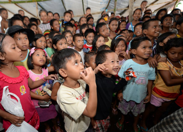 MOSTLY POOR. Young survivors of the Super Typhoon Yolanda (Haiyan) react to a performance by members of Clowns Without Borders as part of recovery work by Plan International at a tent city in Tacloban City, Leyte on Dec 25, 2013. File photo by Ted Aljibe/AFP
